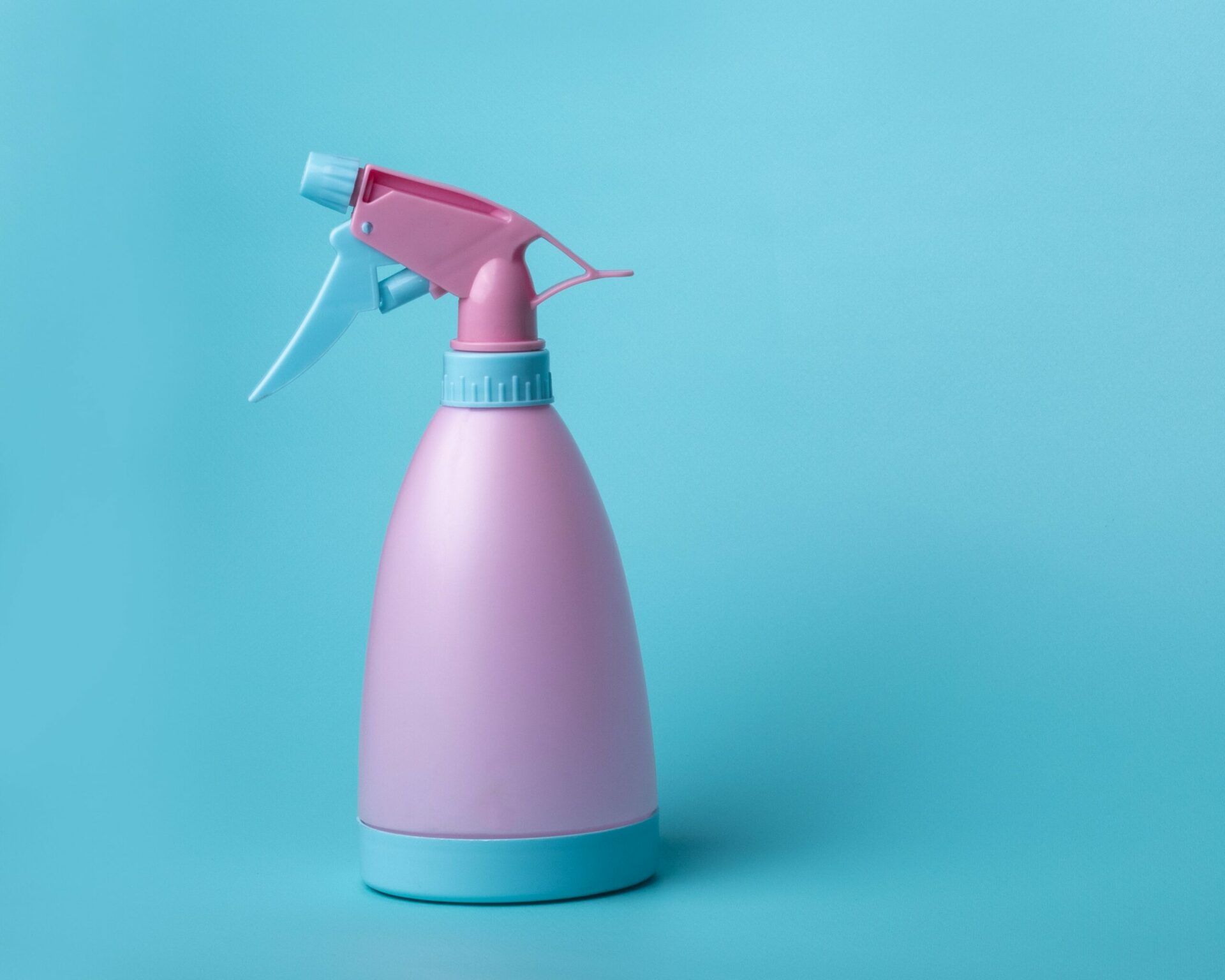 A pink and blue water squirt bottle on a blue background.