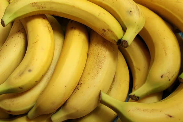A close up of a pile of yellow bananas with some green on their tips and a few brown spots.