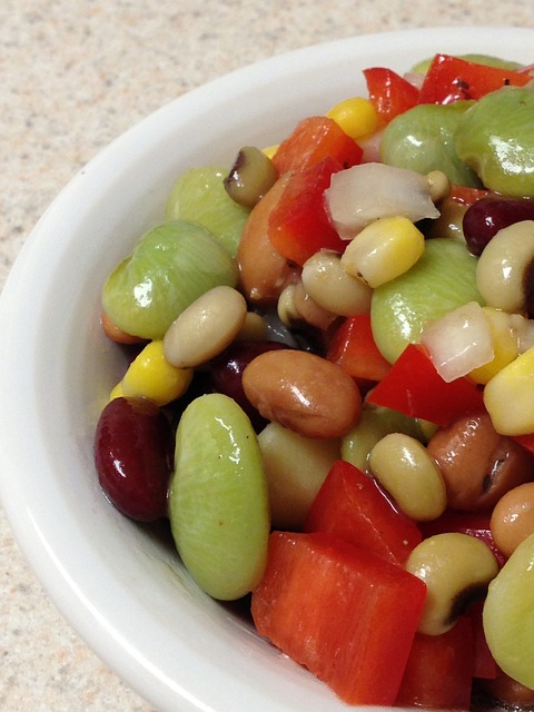 A multibean salad close up which includes lima beans, peppers, onion, corn, black-eyed peas, red kidney beans, and possibly a few other beans. I'm an expert in cat behavior, not in beans, so I'm not entirely sure which bean is which.