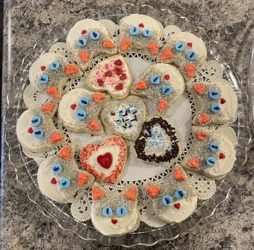 A tray of cookies decorated to look like Zoloft, a lynx point Siamese cat, along with a few heart shaped cookies.