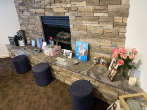 A picture of a fireplace set up for a Zoloft's memorial service There are roses, pictures, a box from Chewy, bowls, his favorite toy, and more in view. I miss him a lot.